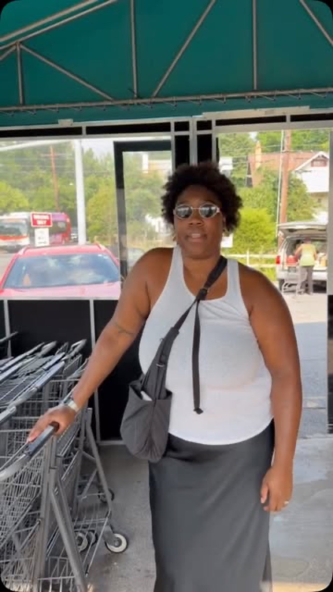 A community member stands outside TPSS Co-op during outreach for a community wealth briefing.
